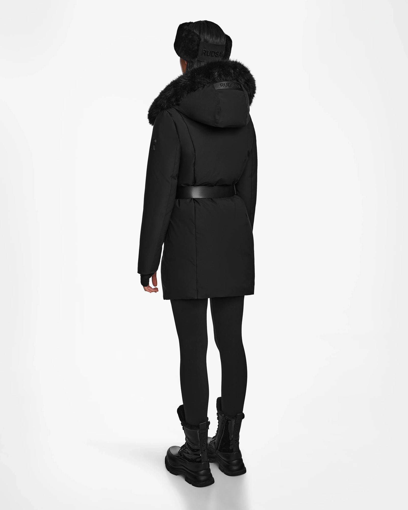 A person faces away, wearing the Rudsak MODA M - 8124555 Black down parka with a fur-trimmed hood and black accessories against a white background—combining warmth and sustainable winter style.