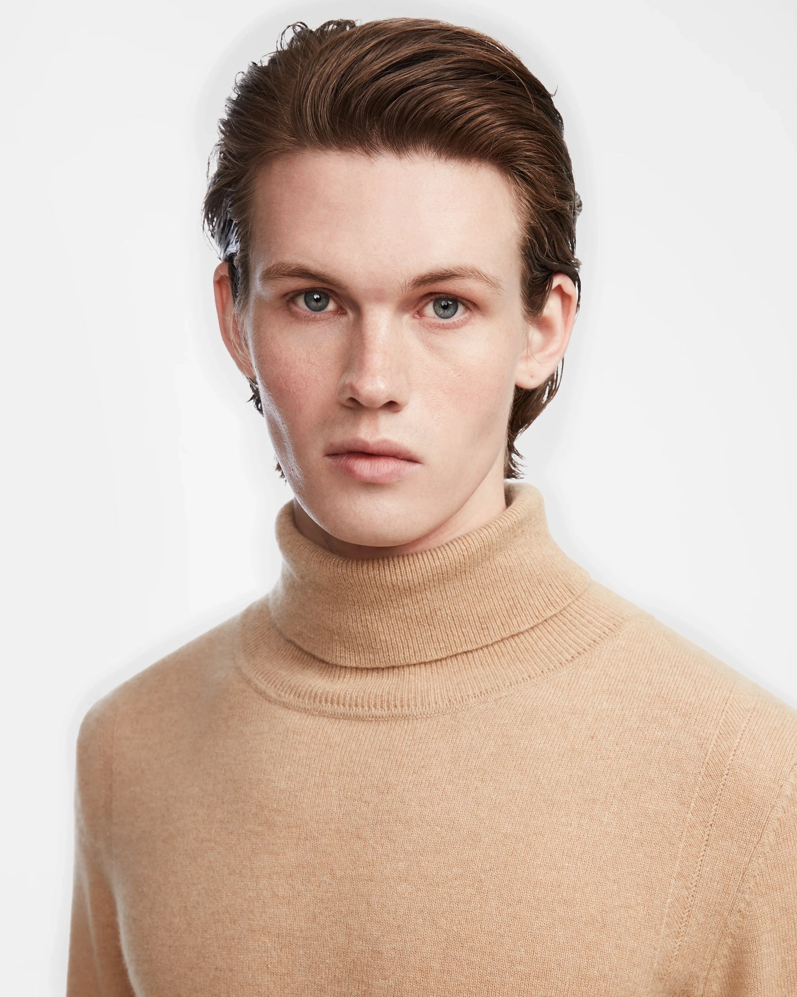 A young person with fair skin and short brown hair wears the Rudsak NICOLAS - 6524528 Camel mens luxury cashmere turtleneck sweater, looking directly at the camera against a plain white background.