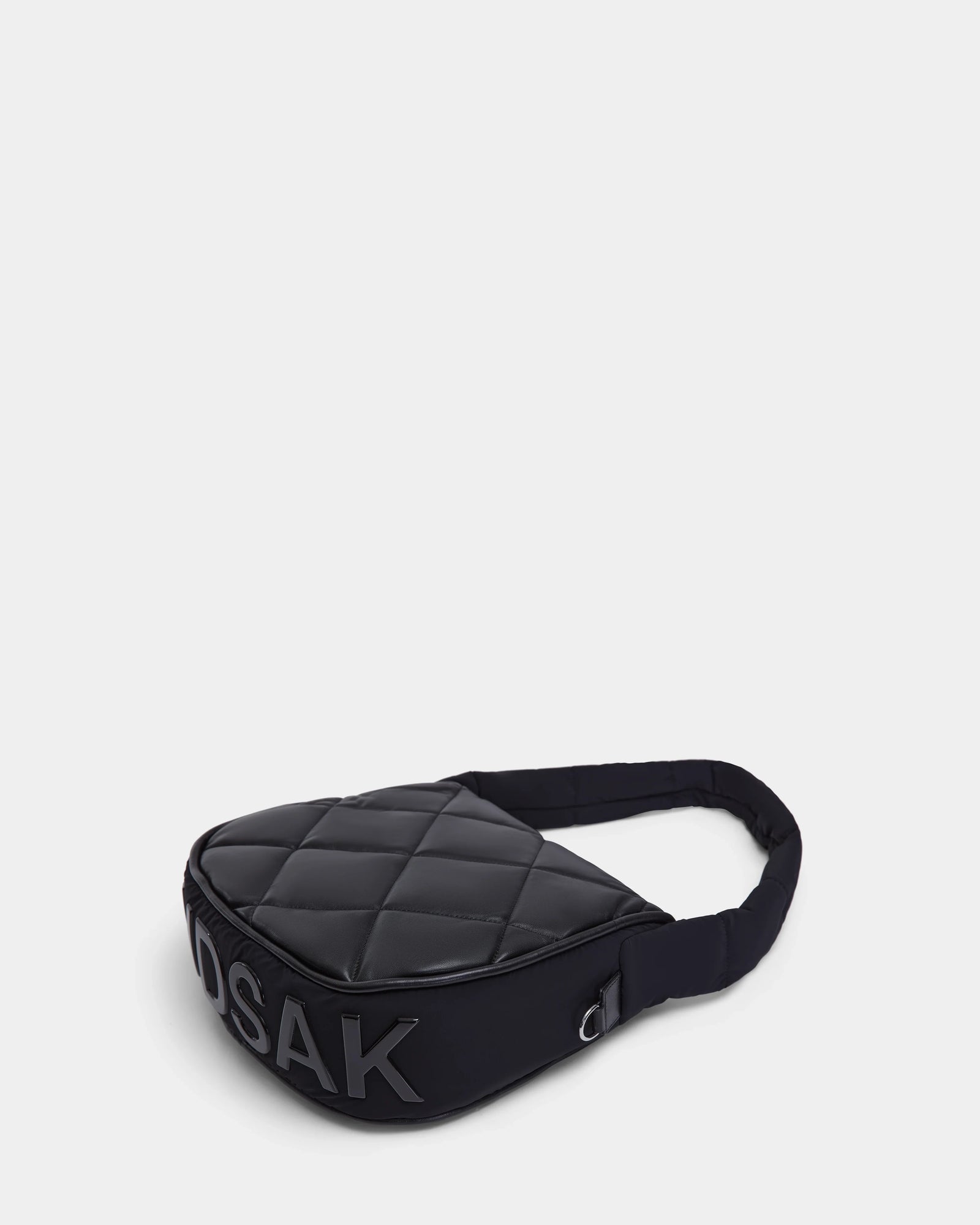 The Rudsak NIOBE L - 8324503 Black sling bag, quilted with a padded strap, is shown on a plain light background. Bold “DSAK” lettering appears prominently on the side.