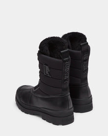 The Rudsak REAGAN - 6224501 Black men’s winter boots feature thick soles, lace-up fronts, soft furry linings, a back pull tab, and the Rudsak name embossed vertically for a stylish finish.