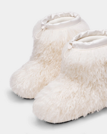 Displayed against a light gray backdrop, the ROSSY - 8224518 Iceland slippers by Rudsak are inspired by Mongolian fur boots, featuring fluffy white faux fur, satin trim, and adjustable ankle drawstrings.