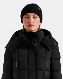 A person faces forward against a plain light gray background, wearing the Rudsak ANDREY - U425507 Black puffer jacket and a black unisex beanie.