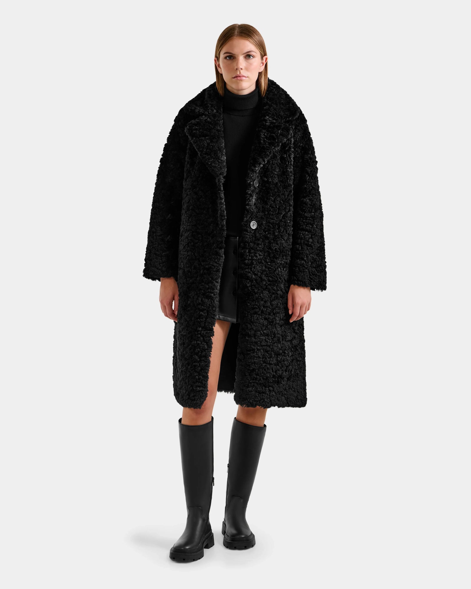 A woman exudes effortless elegance in the Rudsak ANNABELLE FSU - L125512 Black, a stylish women’s reversible trench coat that showcases timeless sophistication.