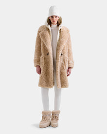 A person stands facing forward against a plain white background, wearing the Rudsak EMRYN - L125588 Vanilla teddy jacket for a cozy winter look.