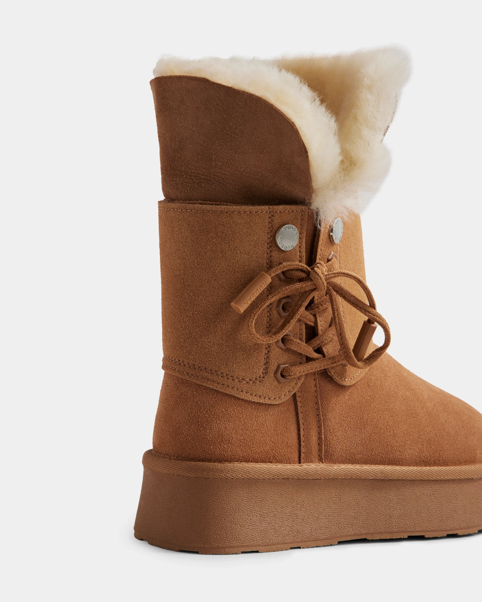 The INESA - L225026 Tan by Rudsak is a women’s suede platform boot with a thick sole, lace-up front, and wool lining. Shown from the side on a white background, these boots offer cozy style for cold days.