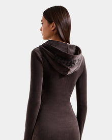 A woman with straight brown hair, seen from the back, wears the Rudsak ISABELLA - L525502 Espresso women’s velour hooded dress featuring rhinestone 