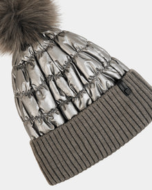 The Rudsak LANYA - L423514 Pewter is a metallic silver quilted women’s pom pom hat with a large faux fur top and wide ribbed gray knit cuff—perfect for standout winter style and cozy warmth.