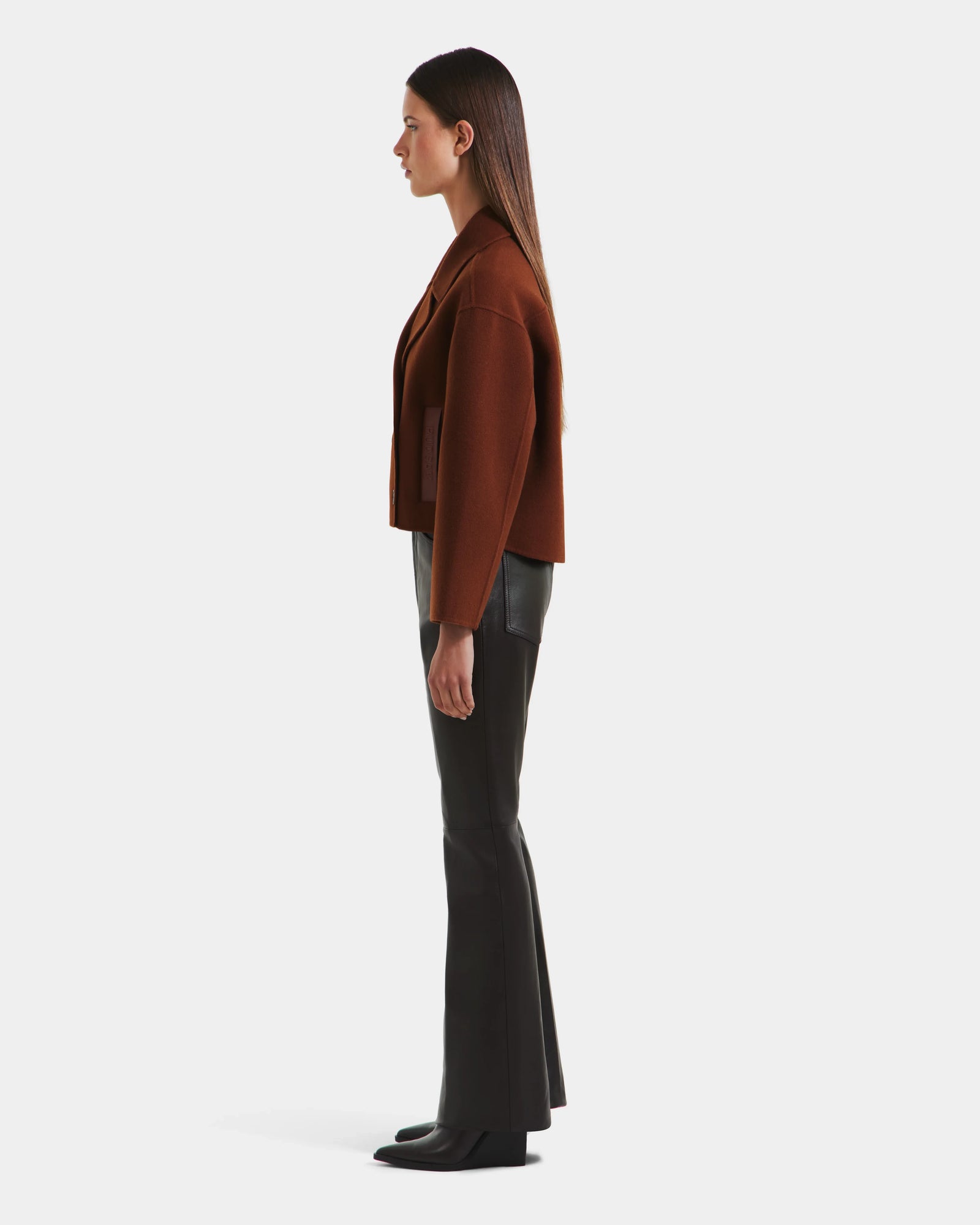 A woman in the Rudsak MARTINEZ - 8125580 Rust stylish brown vegan leather jacket.