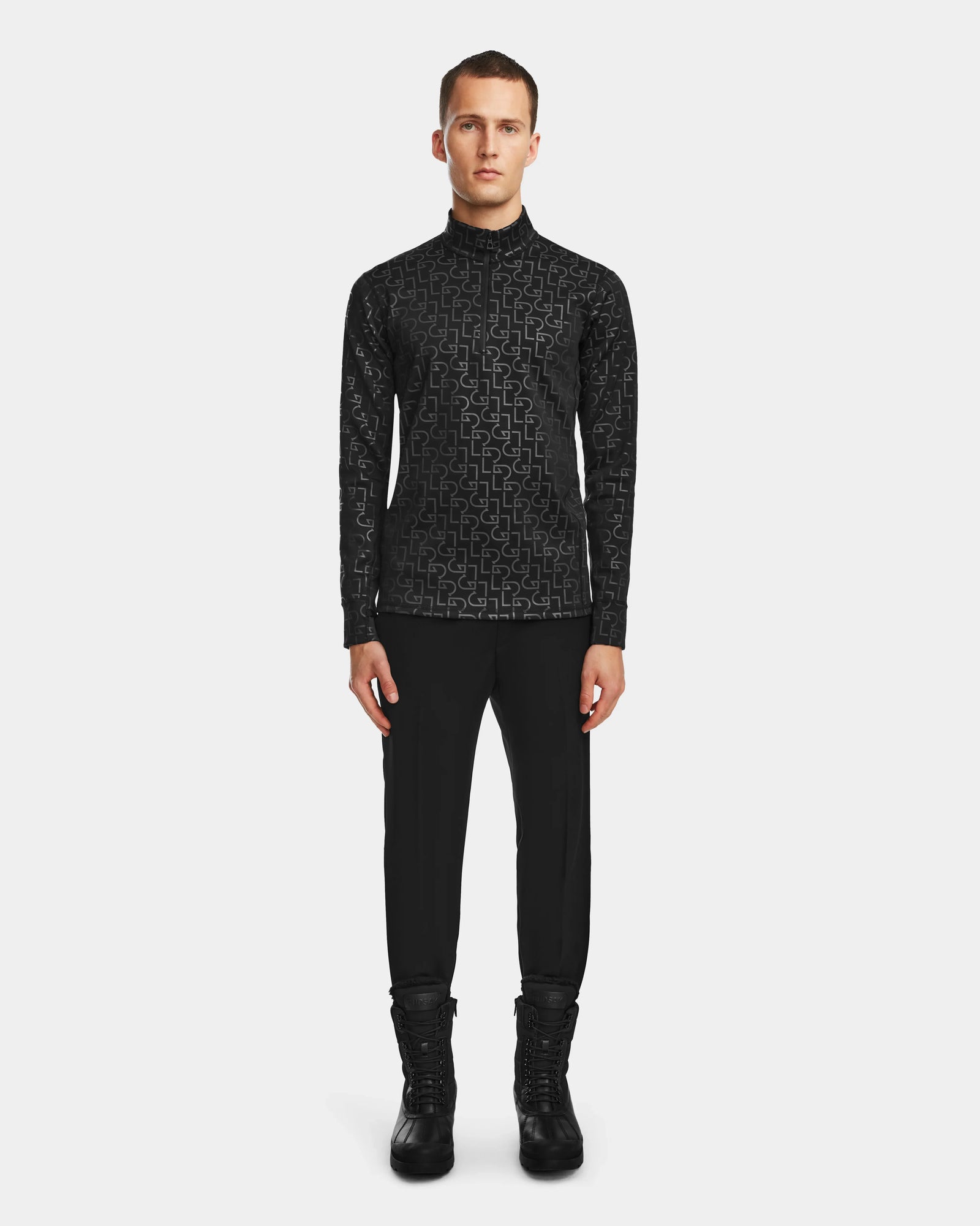 A man faces forward in the Rudsak ROMEO - 6524525 Black mock neck zip-up, black pants, and lace-up boots—showcasing sleek cold-weather activewear against a plain white background.