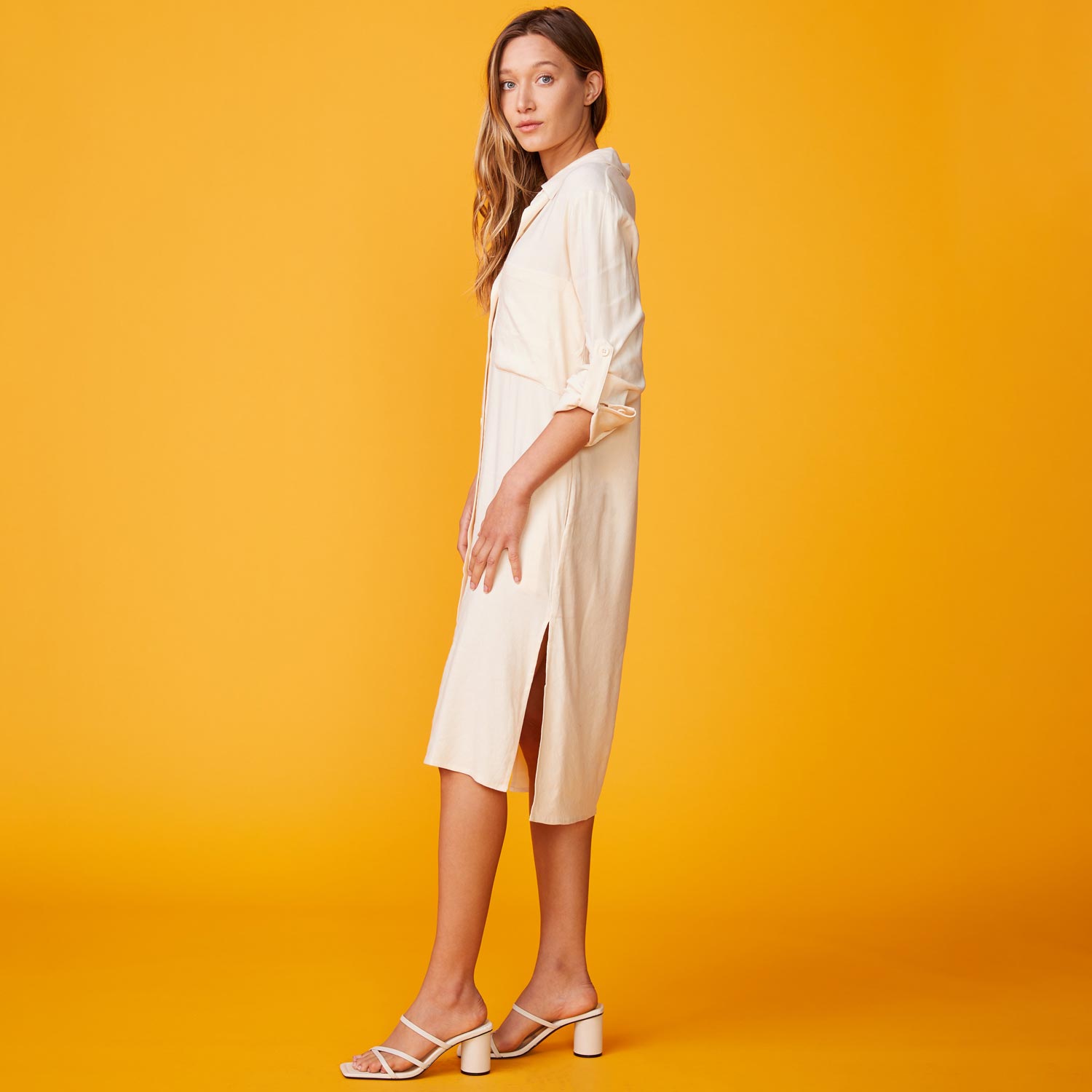 Side view of model wearing the linen shirt dress in buttercream.