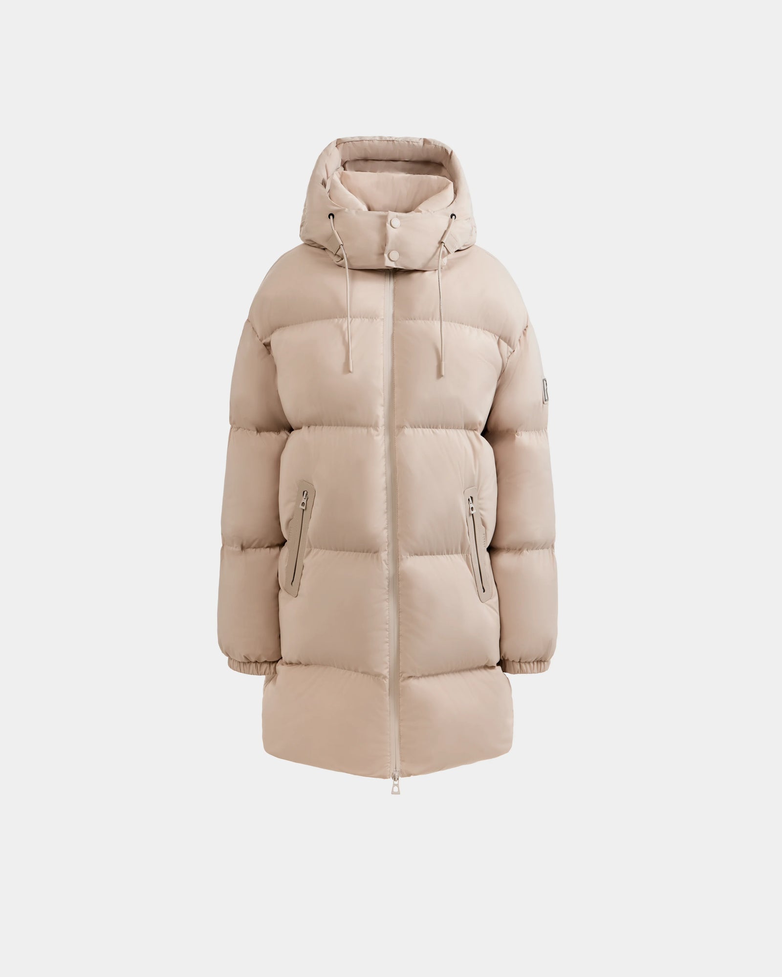 The Rudsak KARLEE L - 8125682 Vanilla is a beige, knee-length women’s long down puffer winter jacket with a hood, front zipper, snap buttons, zippered side pockets, and hood drawstrings, shown against a white background.