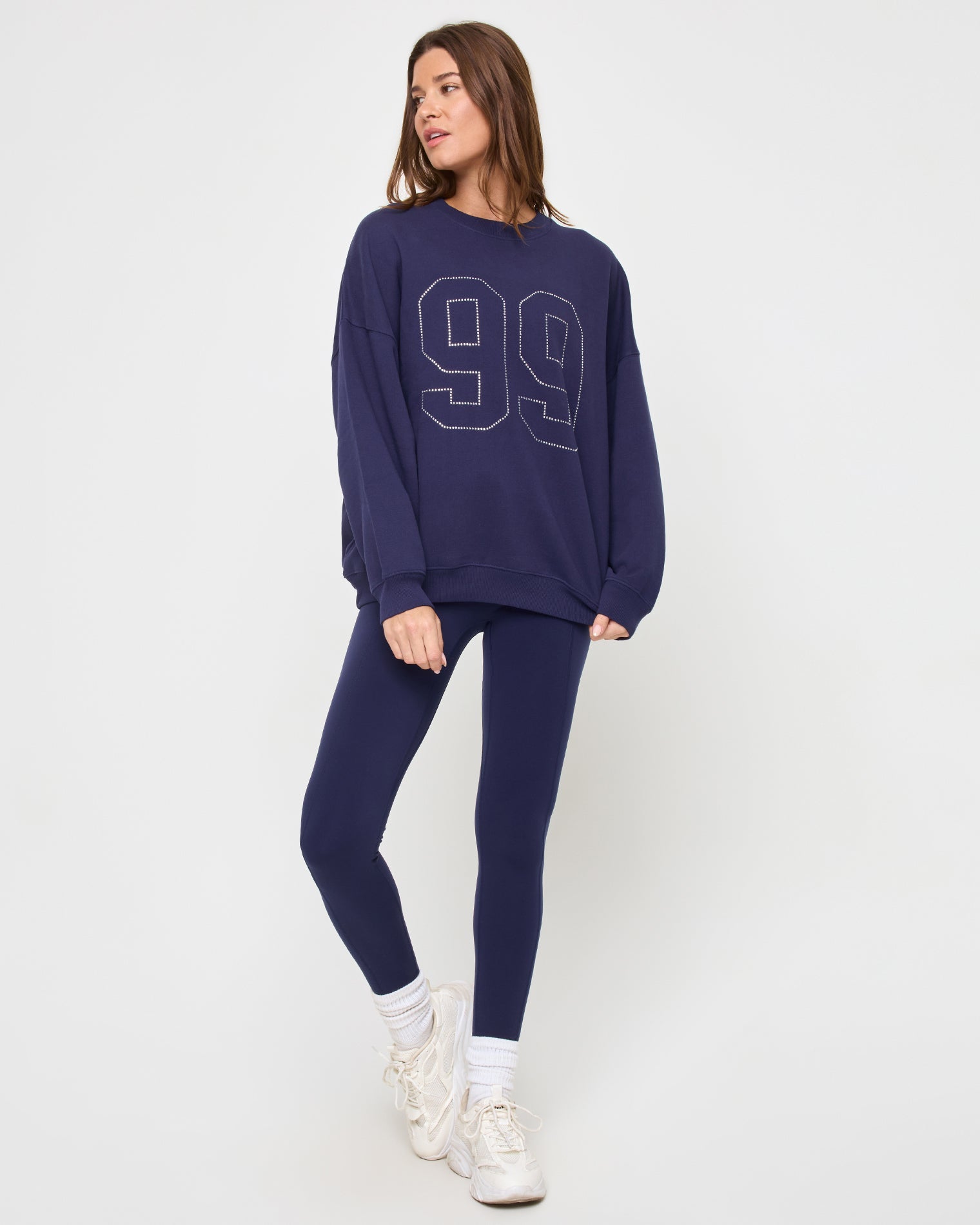 Front view of the LSPACE Legend Sweatshirt in midnight blue on a model against a light background, showing the cropped oversized sweatshirt with rhinestone graphic detail.
