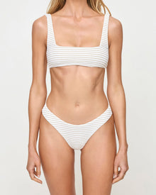 close up view of Woman wearing a white striped bikini against a plain background