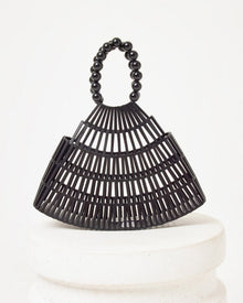 Off-model image of the Starlight Bag in black, a bamboo slat cage-style structured bag with a black beaded handle, on a white pedestal.