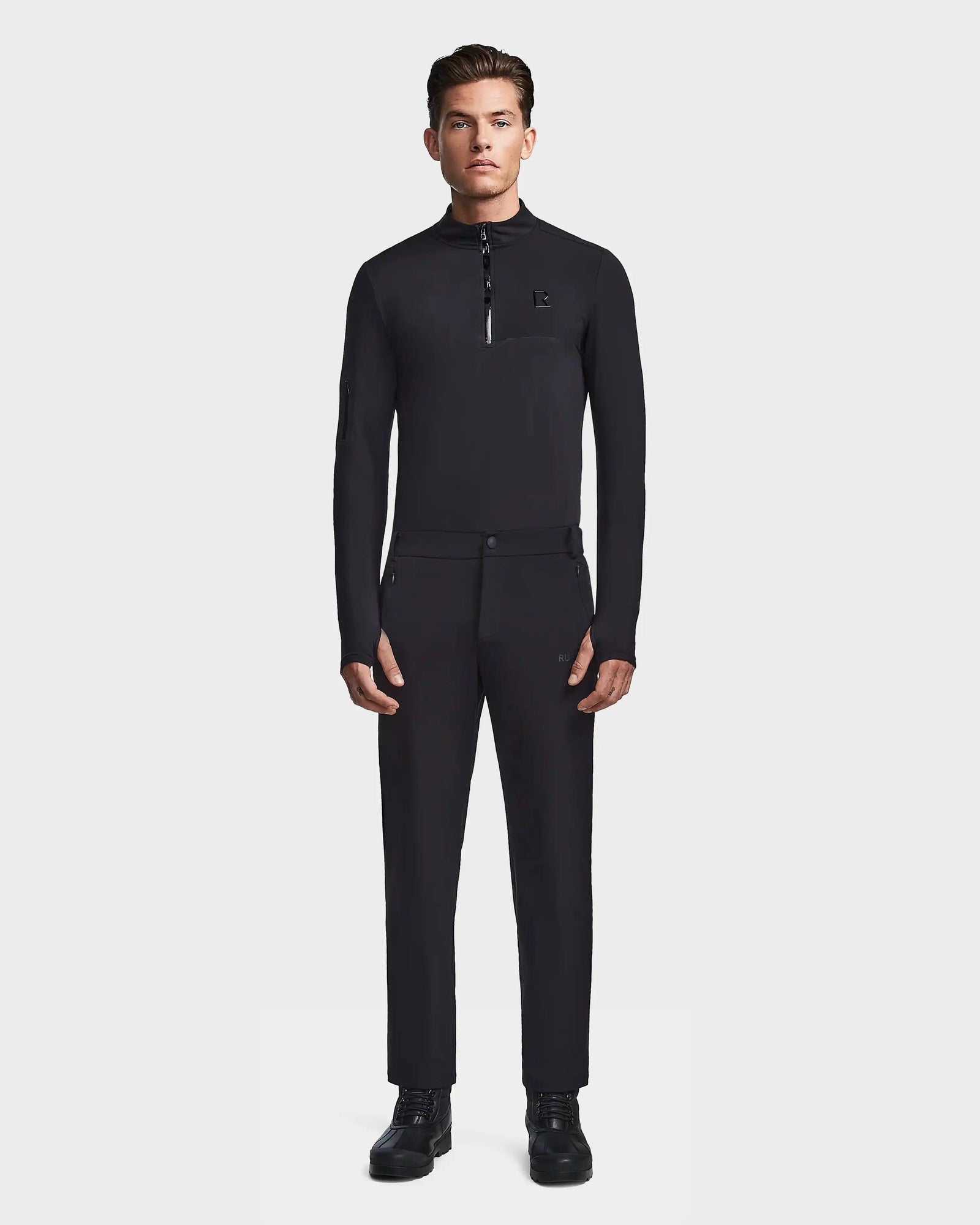 A man stands facing forward in the Rudsak KICO - 6523508 Black fitted long-sleeve zip-collar shirt with tailored pants and black shoes, set against a plain white background.