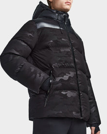 A person wears the Rudsak RONNY M - M123512 Camo Black hooded down puffer jacket with zippered pockets, highlighting stylish, weather-resistant mens outerwear against a plain light background.