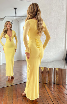Rear view of the yellow maxi dress with sheer long sleeves and a tie-back waist