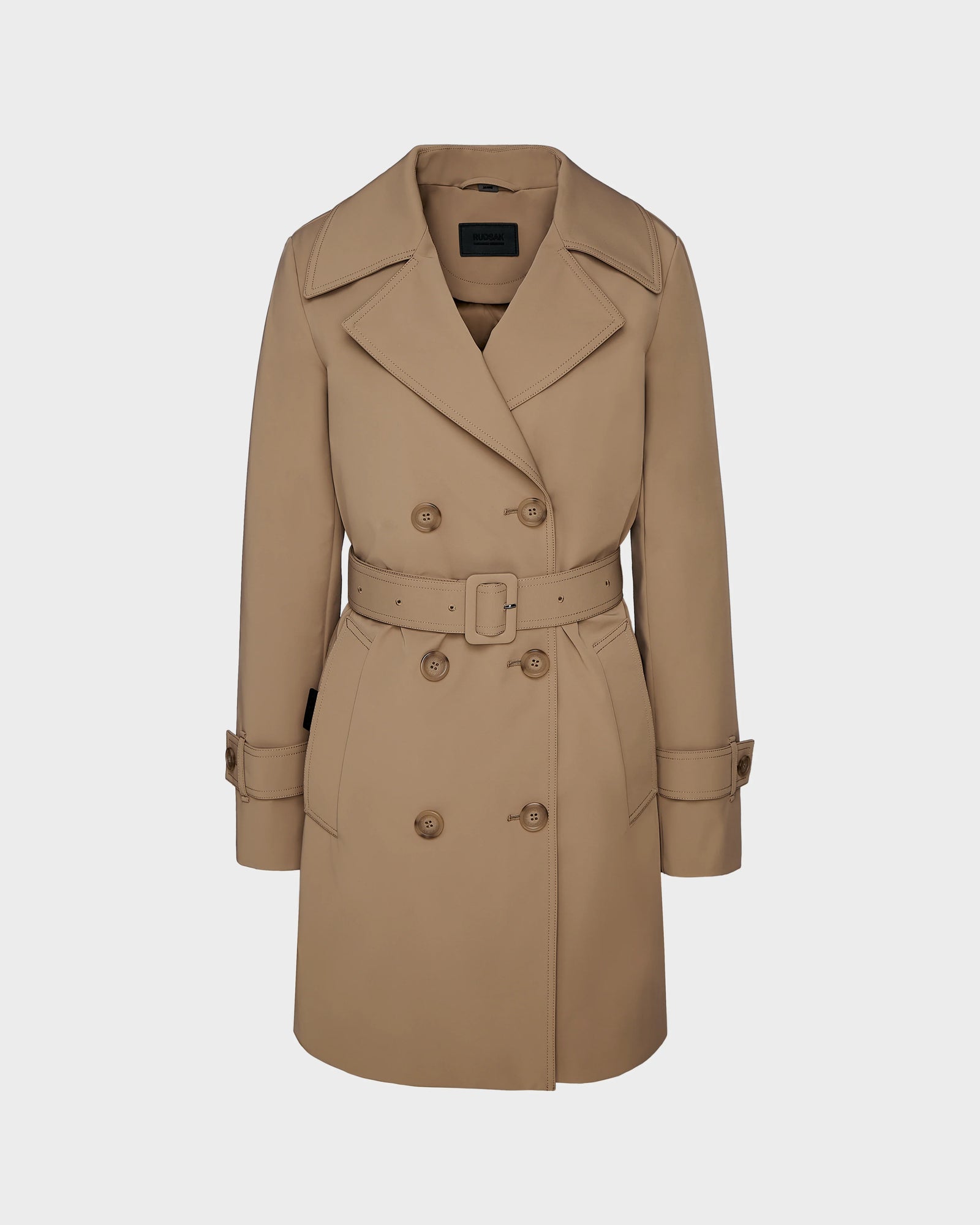 The Rudsak KIMBERLY - 8124801 Camel is a womens camel belted trench coat with wide lapels, buttoned cuffs, and a classic double-breasted design, shown against a plain light background. Timeless and water-repellant for any wardrobe.