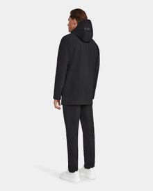 A man faces away from the camera, wearing the Rudsak IAN - 6124009 Black rainwear jacket with matching black pants and white sneakers against a plain light gray background.