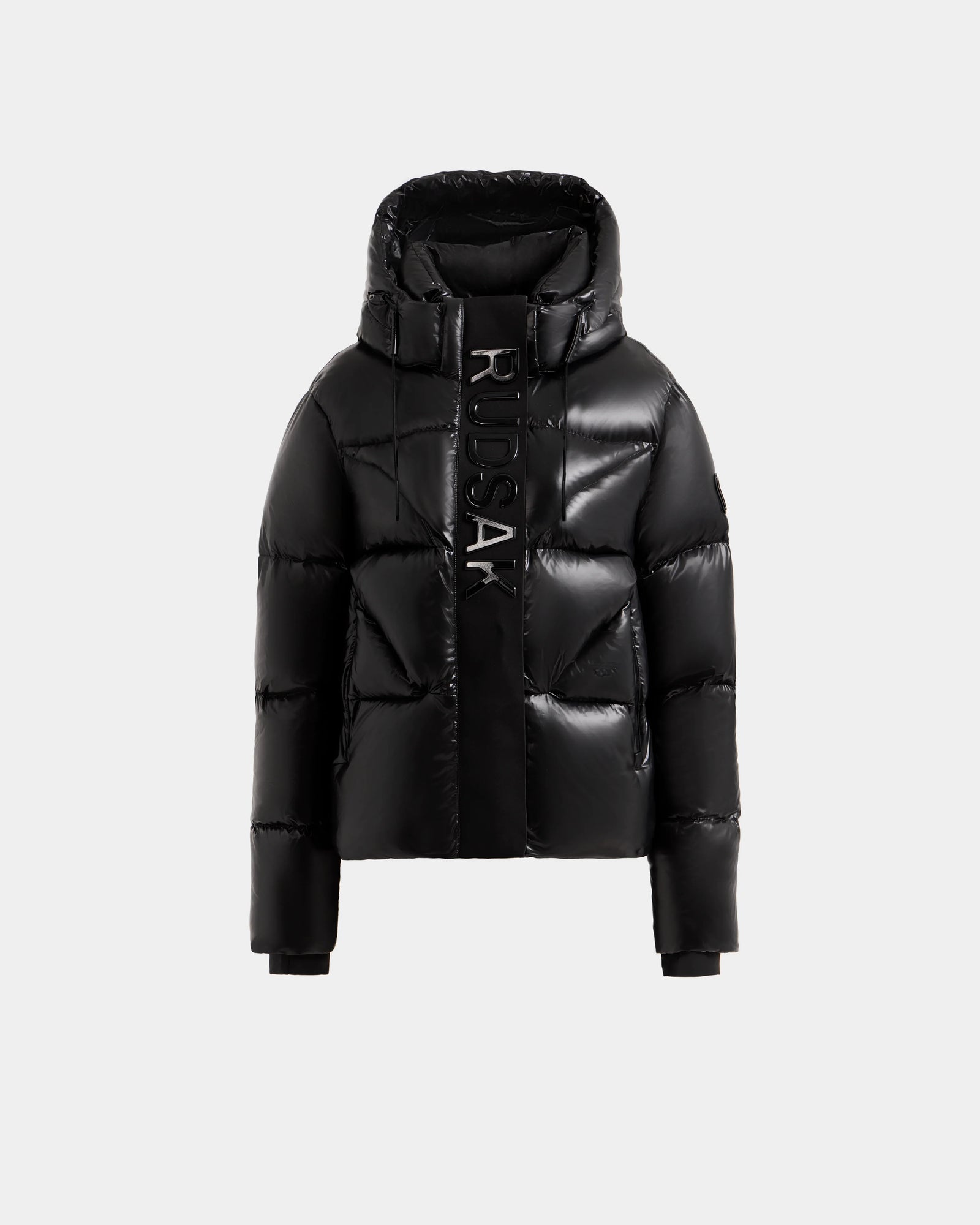 The Rudsak STEFANIE S - L125585 Black is a shiny black women’s short puffer with a high collar, large hood, vertical RUDSAK branding, ribbed cuffs, and quilted down for stylish, weather-resistant warmth.