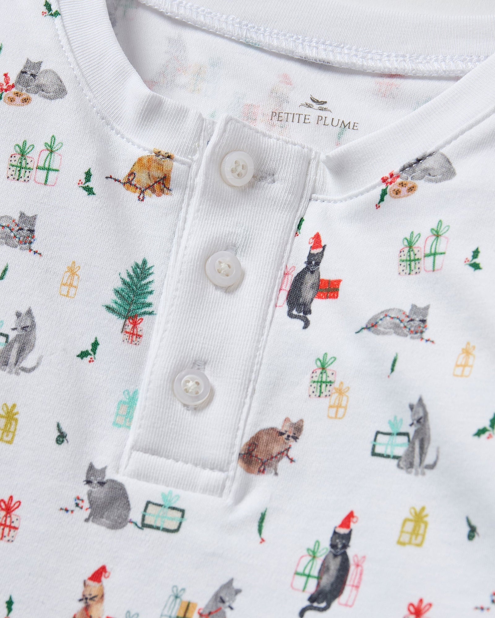 Kid's Pima Snug Fit Pajama Set in Merry Meow features a long-sleeve button-up top and matching pants with winter and holiday-themed prints of cats, trees, presents, and snowmen on a white background.