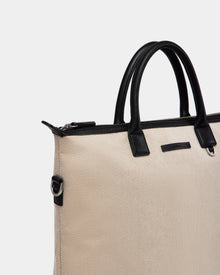 The Rudsak DEXTER - 9324513 Vanilla is a beige textured canvas tote with black leather handles and trim, silver zipper, and metal D-rings—an effortlessly versatile accessory shown against a plain white background.