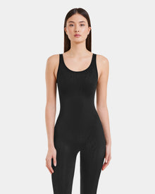 A woman with straight brown hair wears the LAWREN - 8523054 Rudsak Pattern bodysuit by Rudsak, standing confidently against a plain white background.