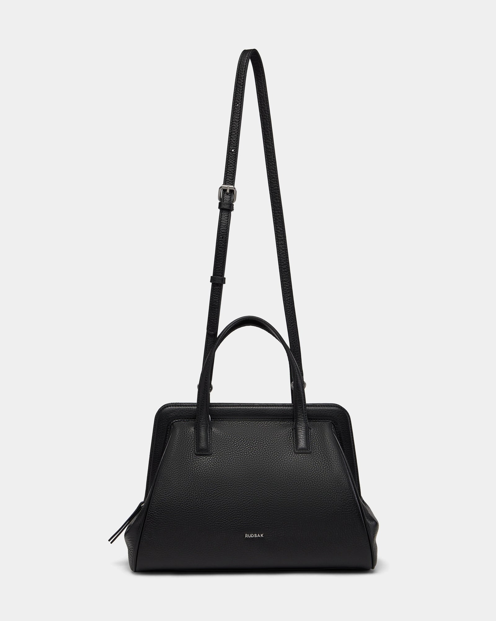 The Rudsak TAULLA - 8325002 Black is a womens pebble leather satchel with two short handles, a removable shoulder strap, spacious interior, structured design, and subtle front branding—shown on a plain white background.