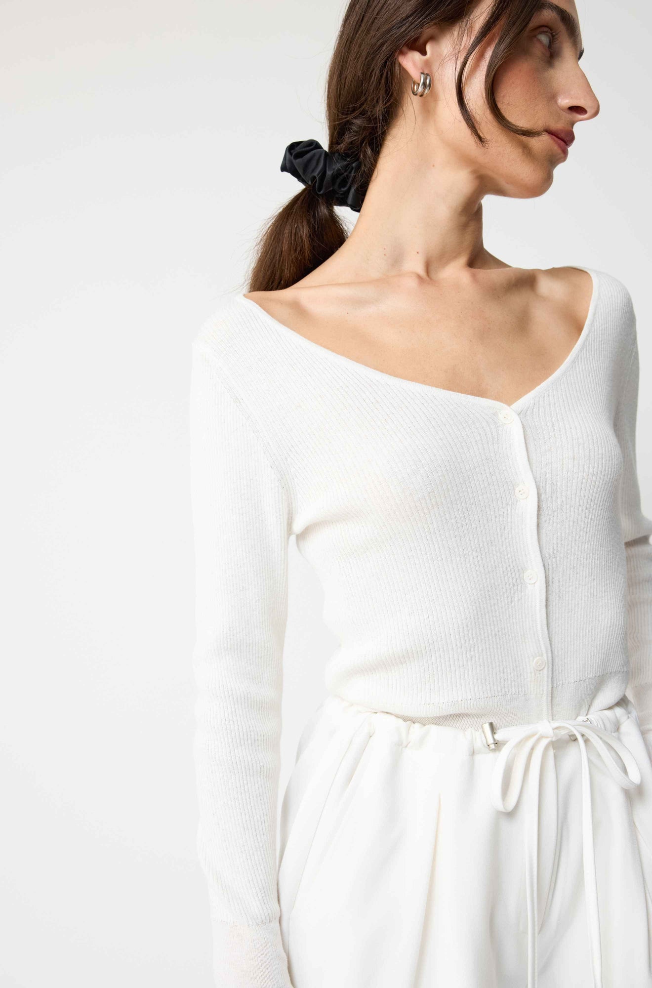 Woman wearing a white long-sleeve top with a plain background