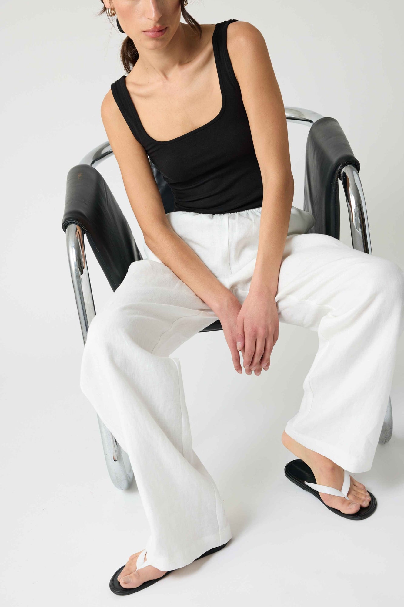 Woman wearing a black square tank top and white linen pants