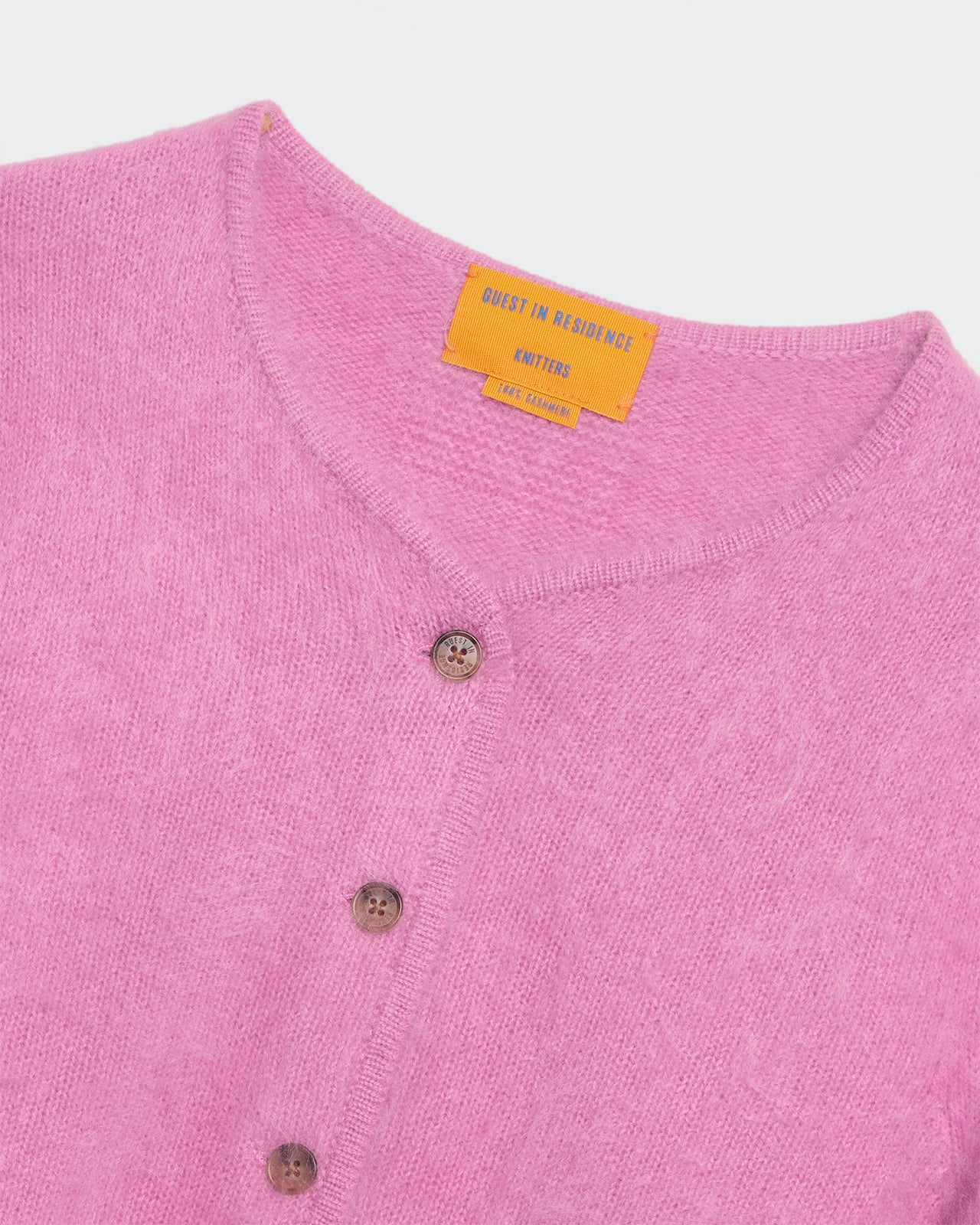 Close-up of a soft rose pink brushed cashmere crew-neck cardigan with button details and rib trim