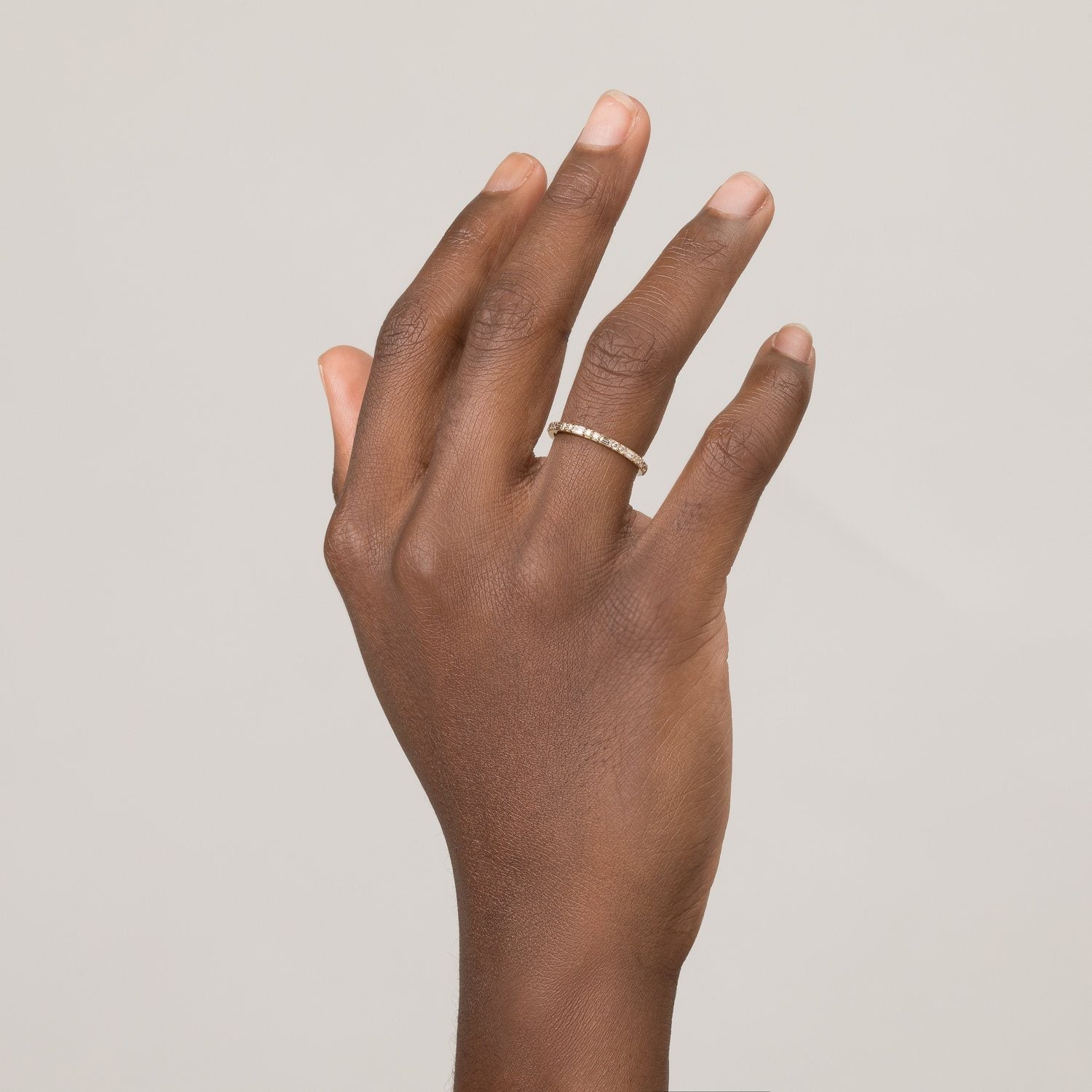 Model. Close up of hand with diamond eternity ring on white background