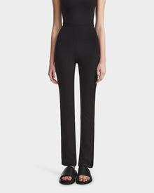 A person wearing the Rudsak ADRIANA - 8524009 Black top and fitted black leggings stands against a plain light background. Only the body from shoulders down is visible; black slide sandals complete the look.