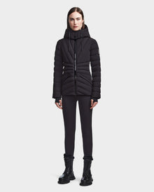 A woman faces forward against a light gray background, wearing the Rudsak HANNA - 8123562 Black winter down jacket with RDS certified down, paired with black leggings and black lace-up boots.