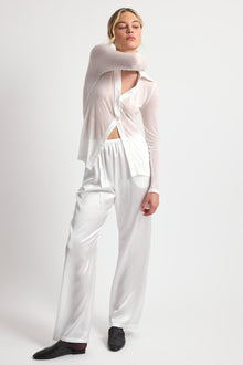 Woman wearing a white outfit with a cut-out design on a plain background