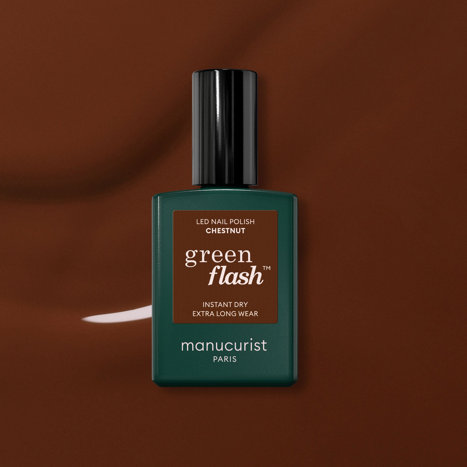 A green Manucurist bottle of Green Flash™ gel polish in Chestnut, a warm brown shade, is set against a glossy brown background.