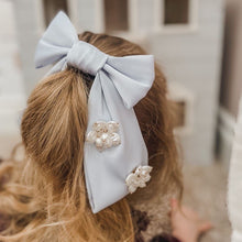 Girl wearing large blue satin hair bow with flower embellishment